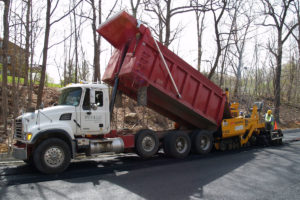 Dump truck loading asphalt into a paver.