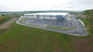 A newly constructed warehouse with paved parking and access roads surrounding it.