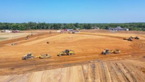 Aerial view of heavy construction equipment levelling and grading the land at Segme Showplace construction site.