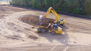 Excavator loading top soil into a dump truck.